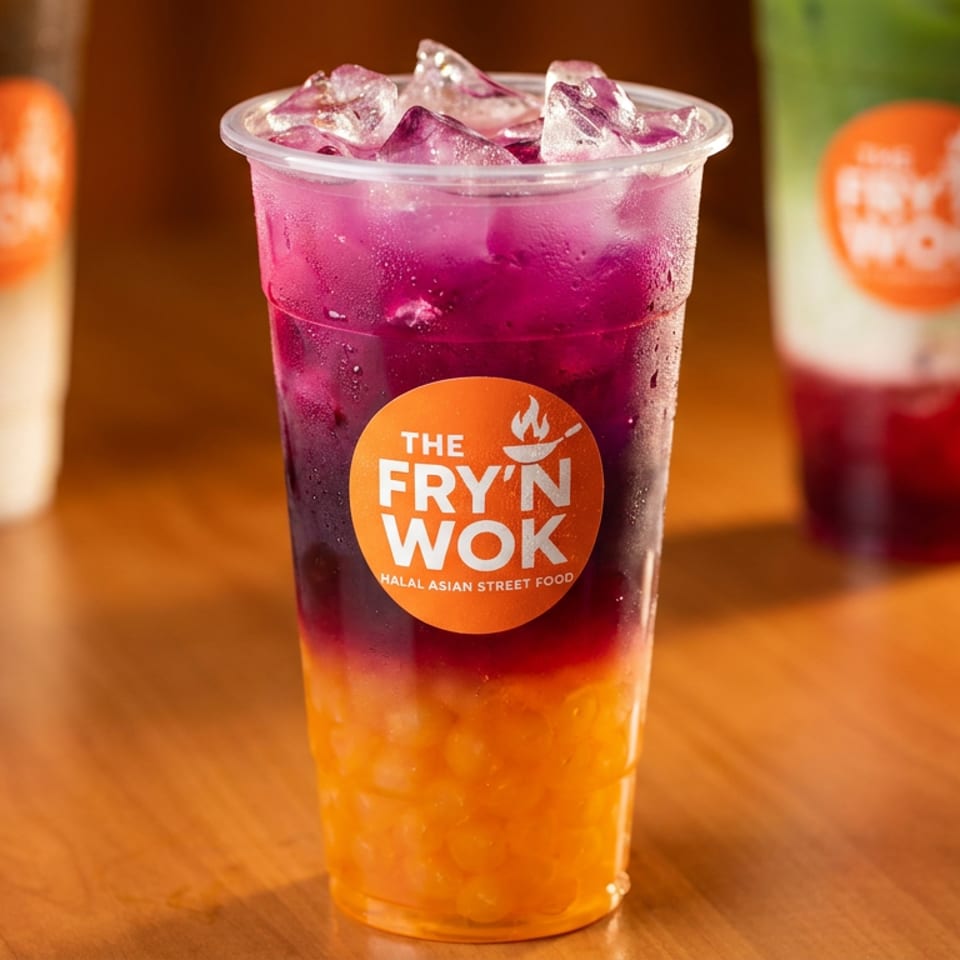 A vibrant purple and orange layered drink with ice and boba from The Fry'n Wok.
